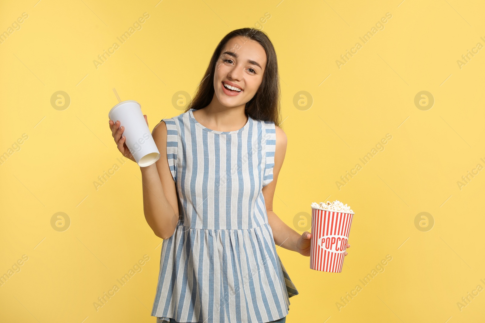 Photo of Woman with popcorn and beverage during cinema show on color background