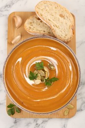 Photo of Delicious pumpkin soup served on white marble table, top view