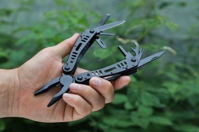 Photo of Man holding compact portable multitool outdoors, closeup