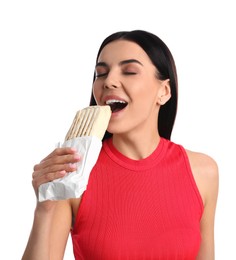 Young woman eating delicious shawarma on white background