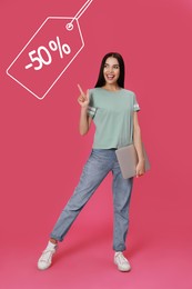 Image of Happy woman pointing at tag with discount on pink background. Special promotion
