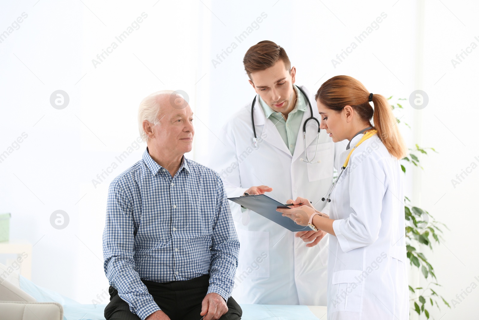 Photo of Doctor and medical assistant working with elderly patient in hospital