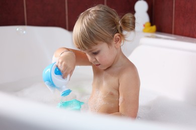 Little girl bathing in tub at home