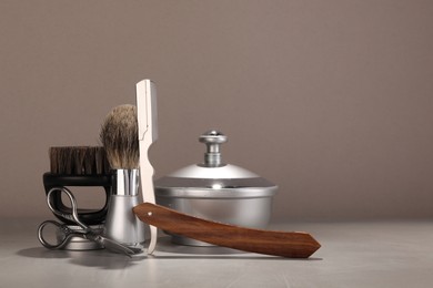 Moustache and beard styling tools on grey table. Space for text