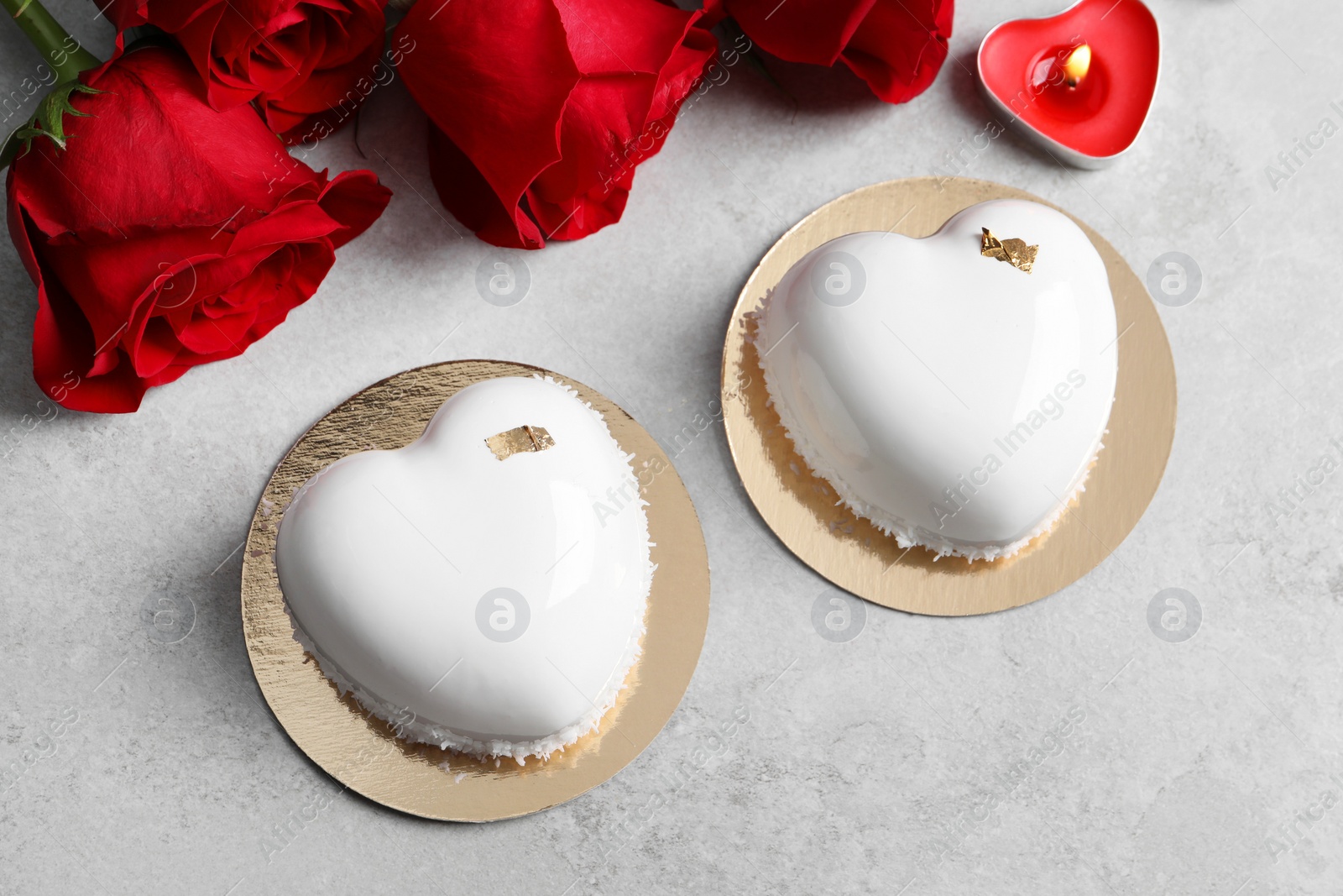 Photo of St. Valentine's Day. Delicious heart shaped cakes, candle and roses on light table, flat lay