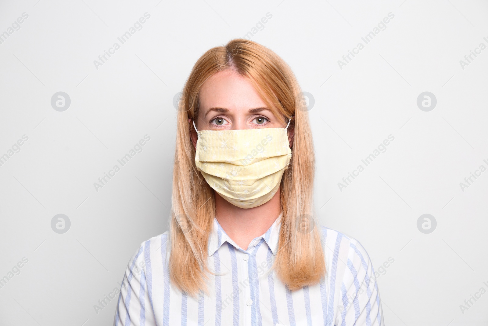 Photo of Woman wearing handmade cloth mask on white background. Personal protective equipment during COVID-19 pandemic