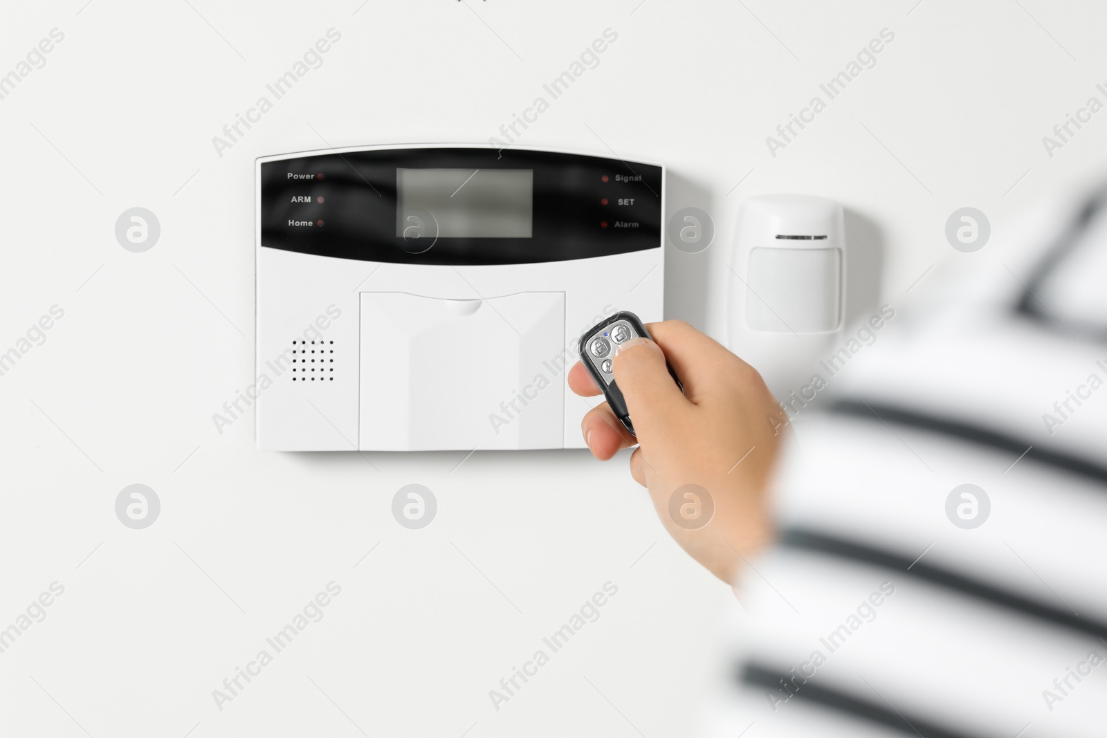 Photo of Home security system. Man using alarm key fob indoors, closeup