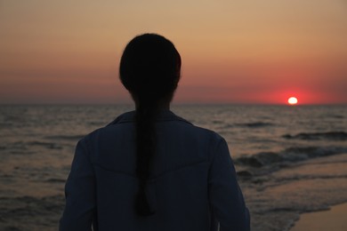 Girl near sea at sunset, back view