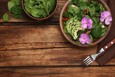 Photo of Fresh spring salad with flowers served on wooden table, flat lay. Space for text