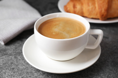 Photo of Tasty fresh croissant and coffee on grey table, closeup