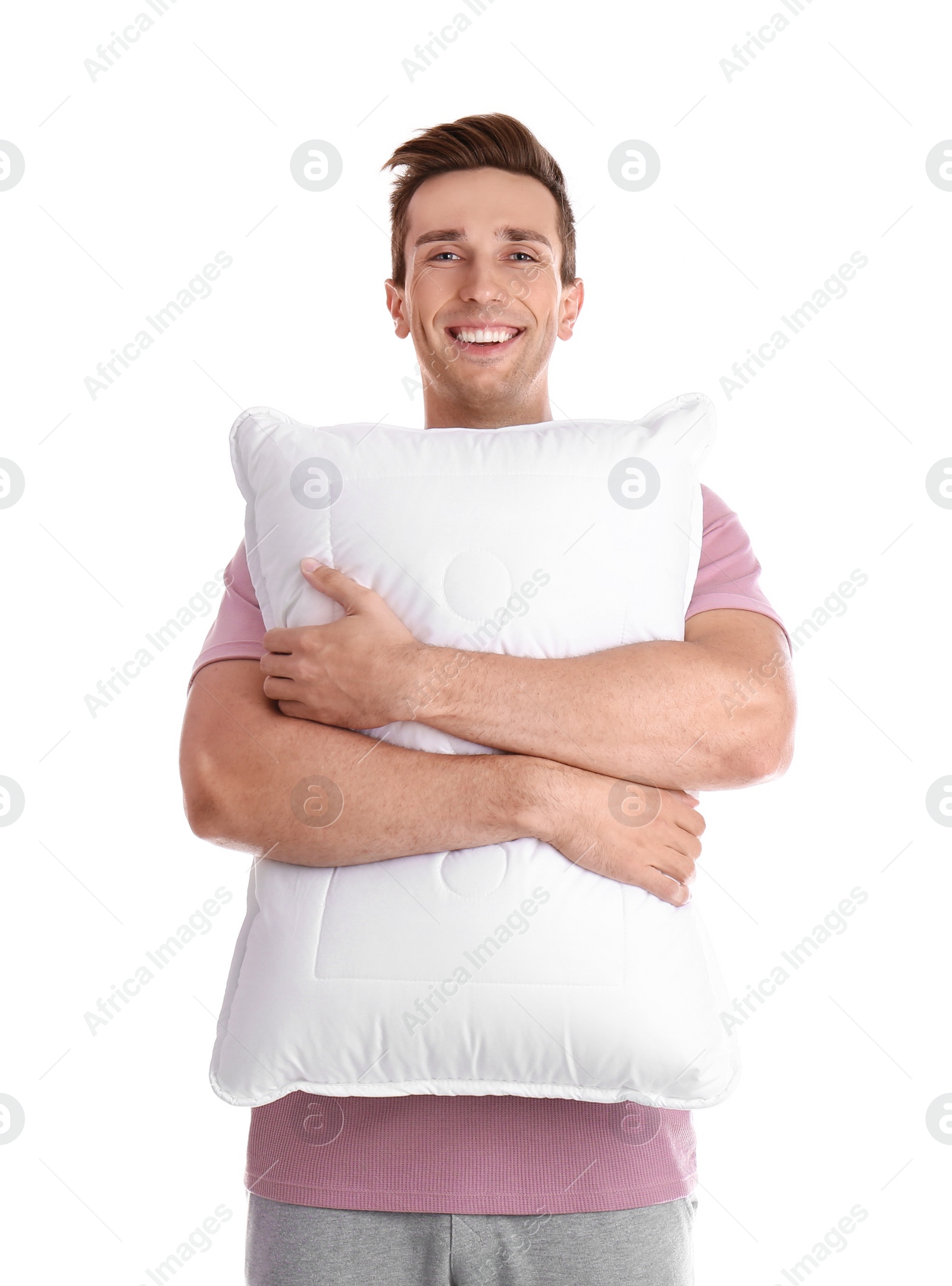 Photo of Young man in pajamas embracing pillow on white background