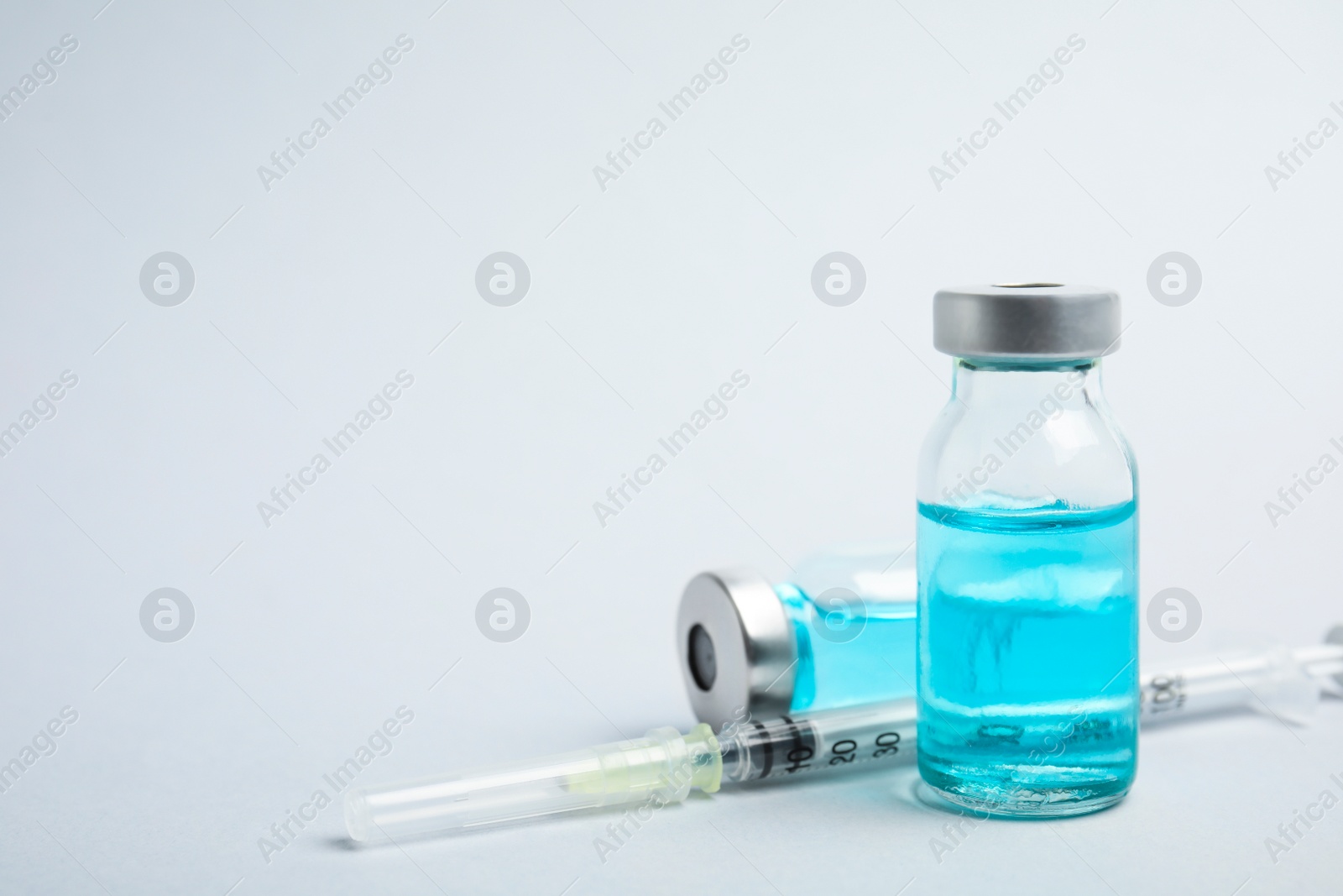 Photo of Vials and syringe on light background, space for text. Vaccination and immunization