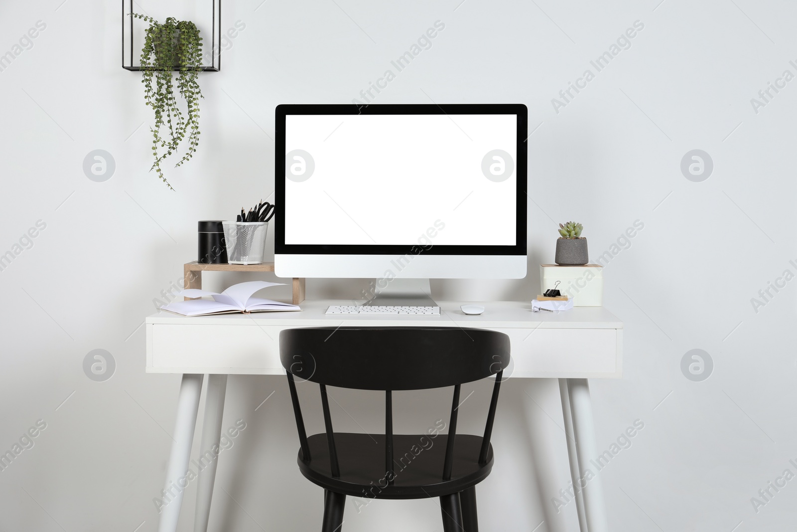 Photo of Cozy workspace with computer, houseplants and stationery on wooden desk at home