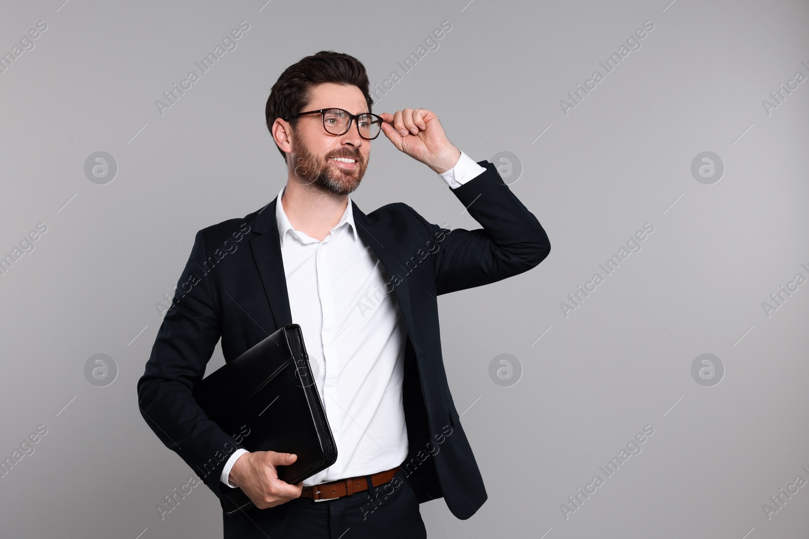 Photo of Happy real estate agent with leather portfolio on grey background. Space for text