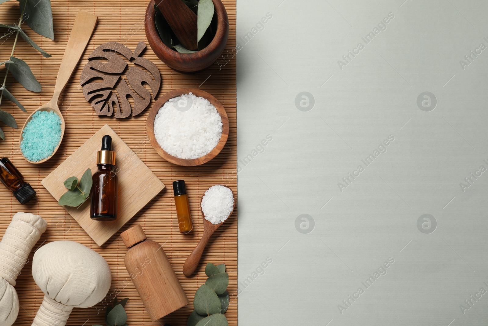 Photo of Different aromatherapy products and eucalyptus leaves on grey background, flat lay. Space for text