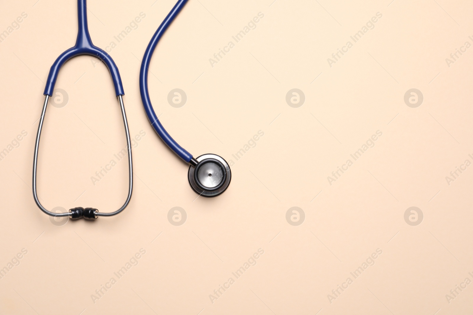 Photo of Stethoscope on beige background, top view. Space for text