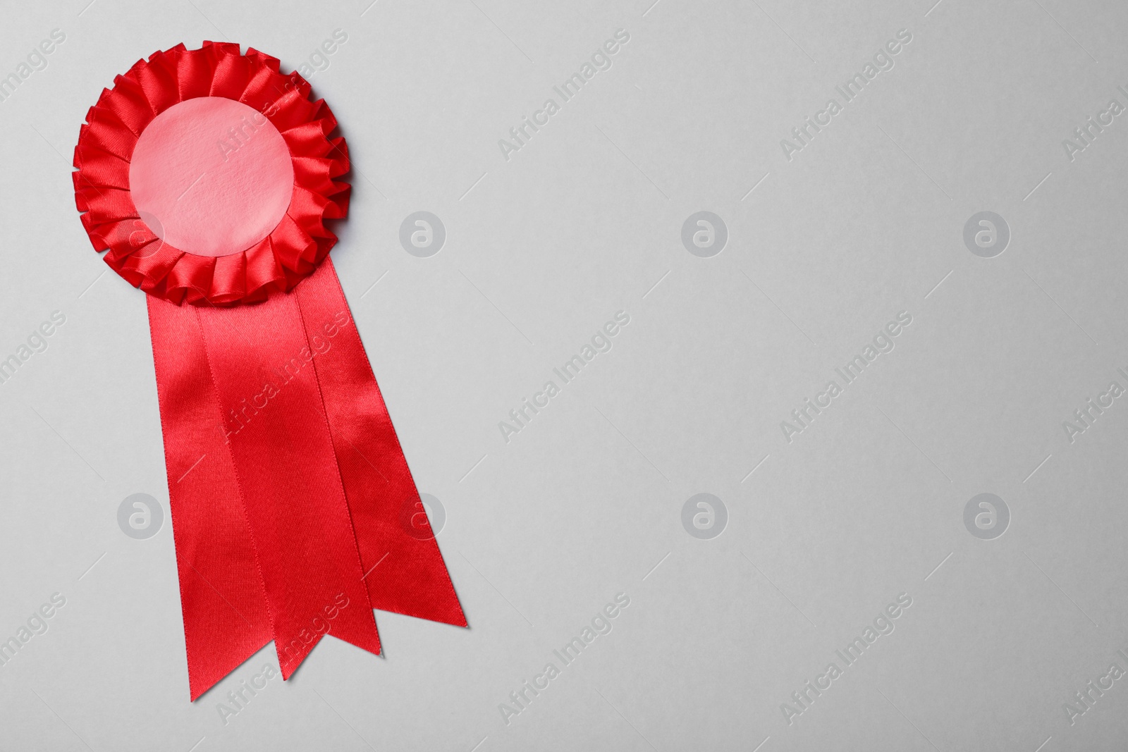 Photo of Red award ribbon on grey background, top view. Space for text