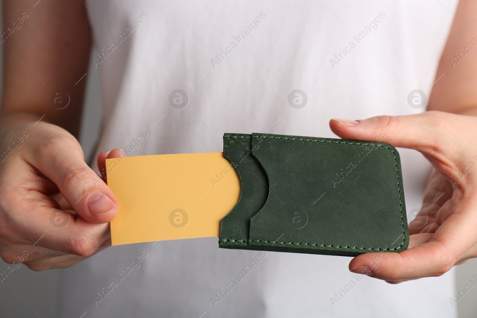 Photo of Woman holding leather business card holder with card, closeup