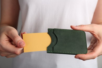 Photo of Woman holding leather business card holder with card, closeup