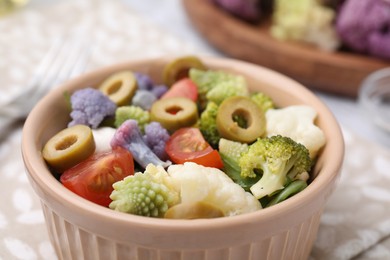 Photo of Delicious salad with cauliflower, tomato and olives on table, closeup