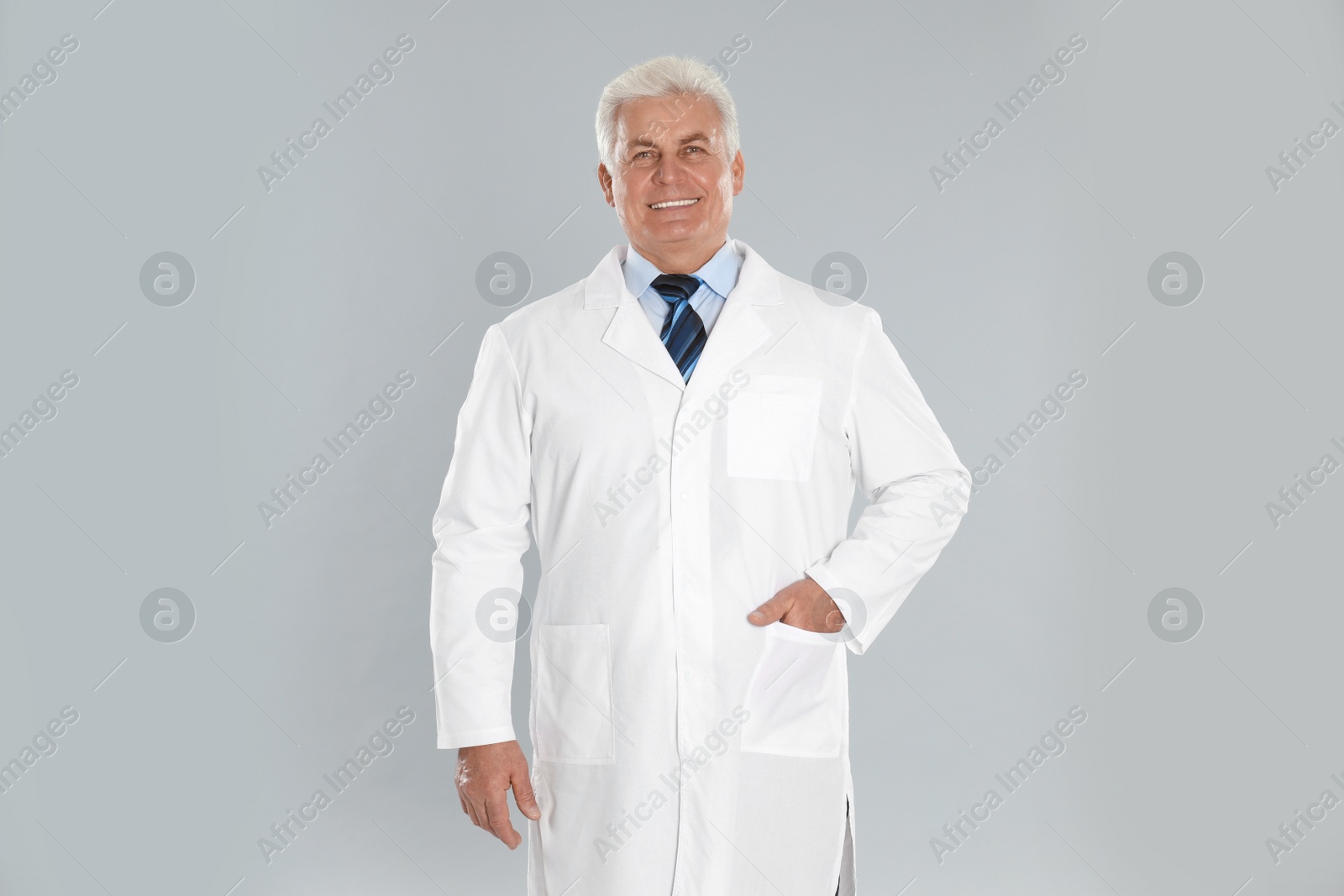 Photo of Happy senior man in lab coat on light grey background