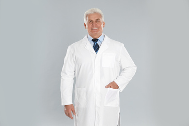 Photo of Happy senior man in lab coat on light grey background