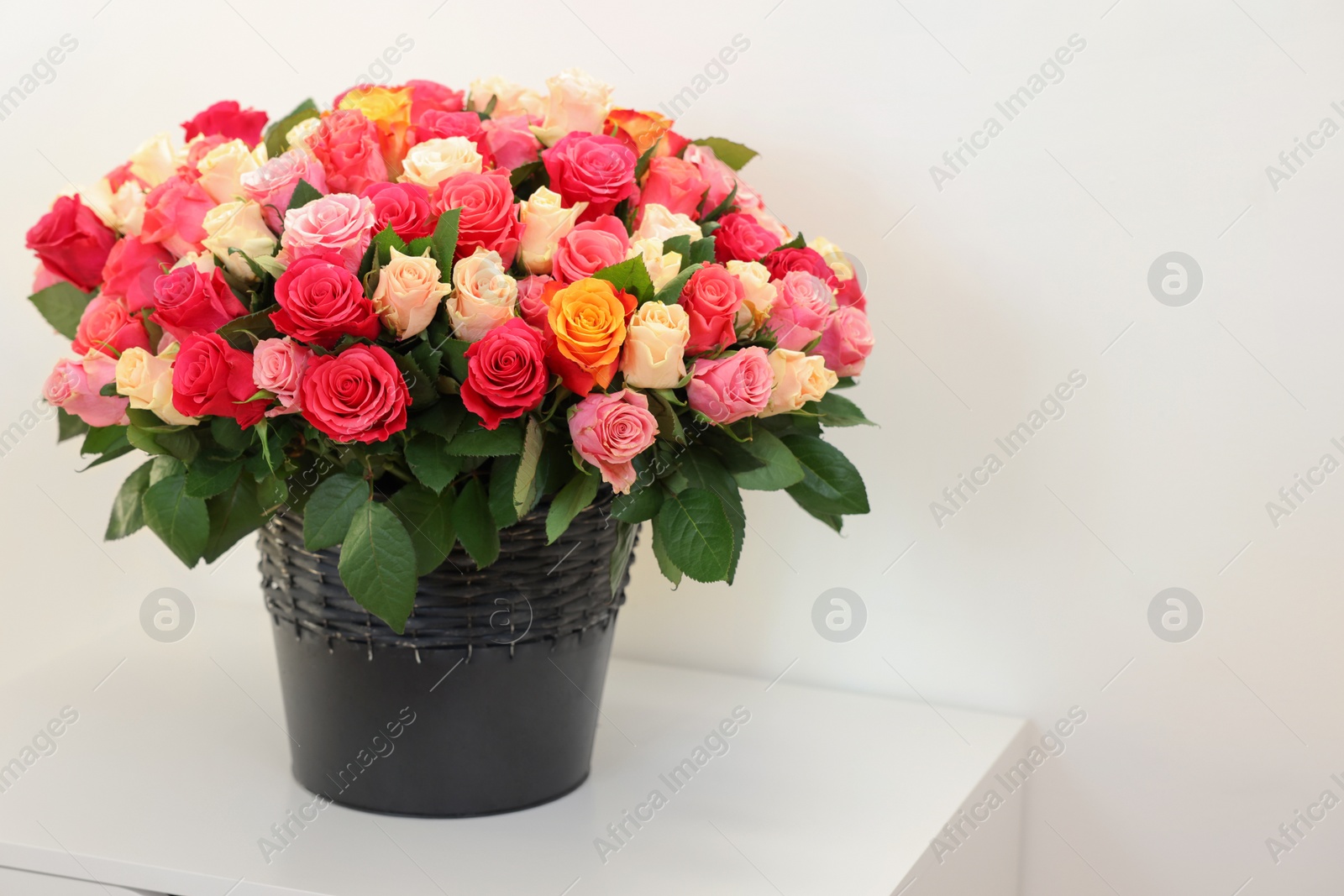 Photo of Bouquet of beautiful roses on white bedside table, space for text