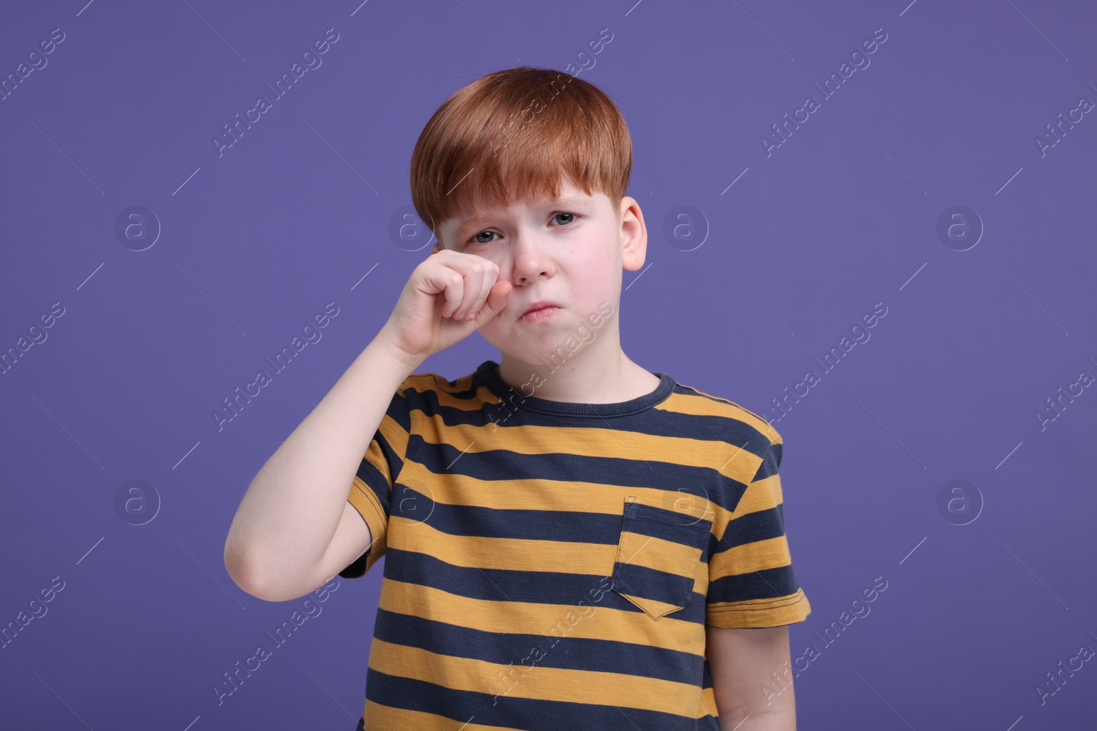 Photo of Portrait of sad little boy on purple background