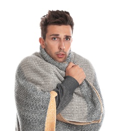 Young man wrapped in warm blanket suffering from cold on white background