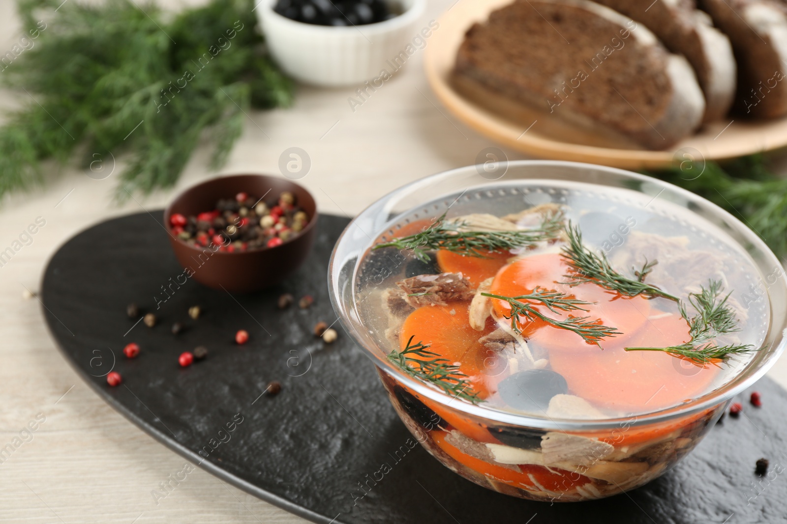 Photo of Delicious aspic with meat and vegetables served on light wooden table, closeup