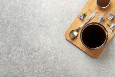 Glass cup of delicious chicory drink, powder and flowers on light grey table, top view. Space for text