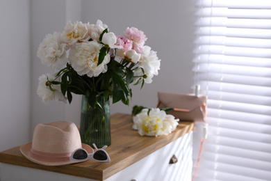 Photo of Bouquet of beautiful peony flowers on chest of drawers indoors. Space for text