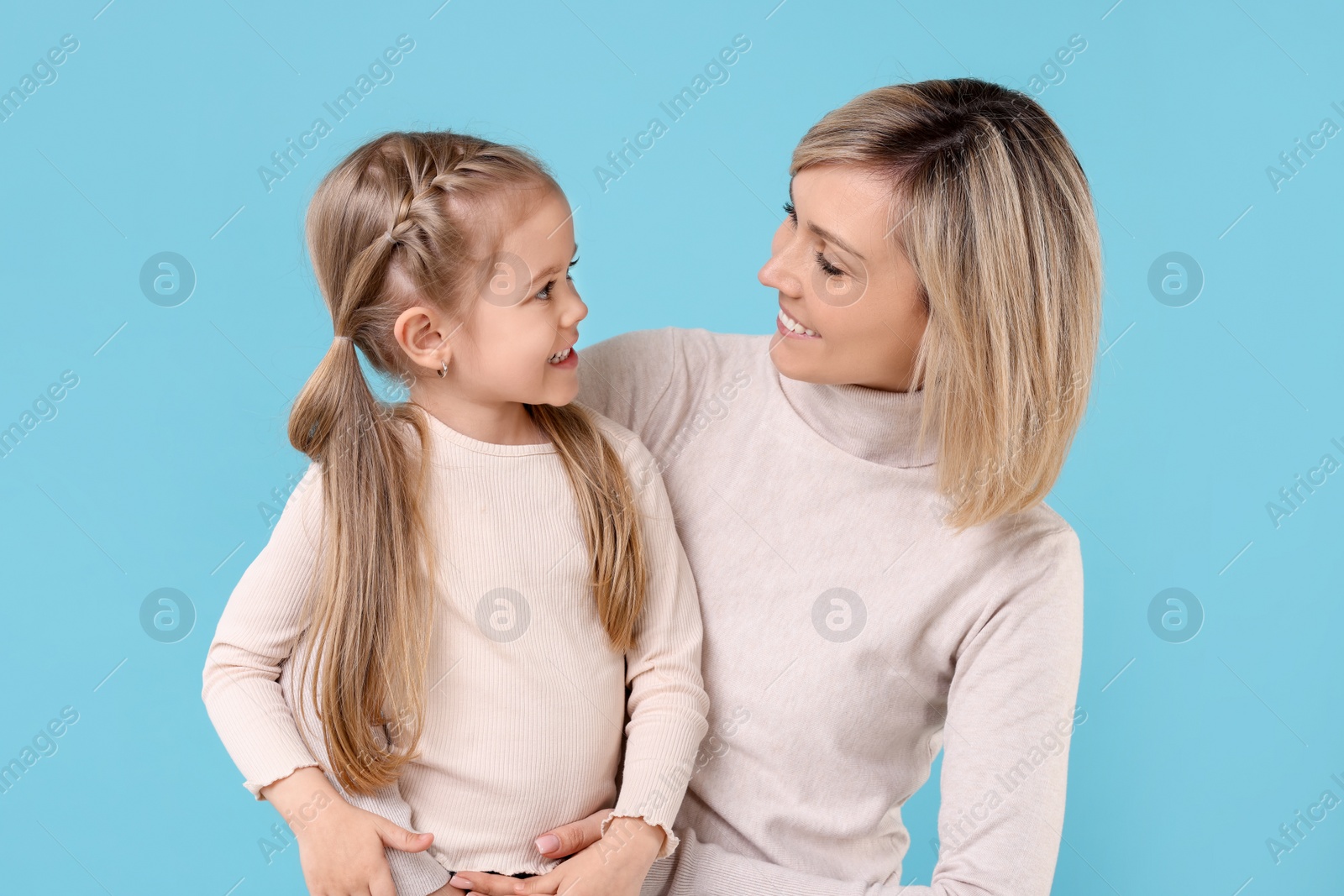 Photo of Happy mother and daughter on light blue background