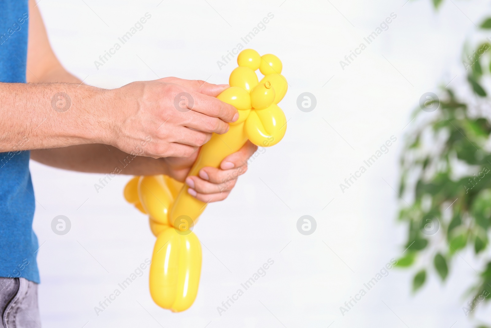 Photo of Man making balloon figure on blurred background, closeup. Space for text