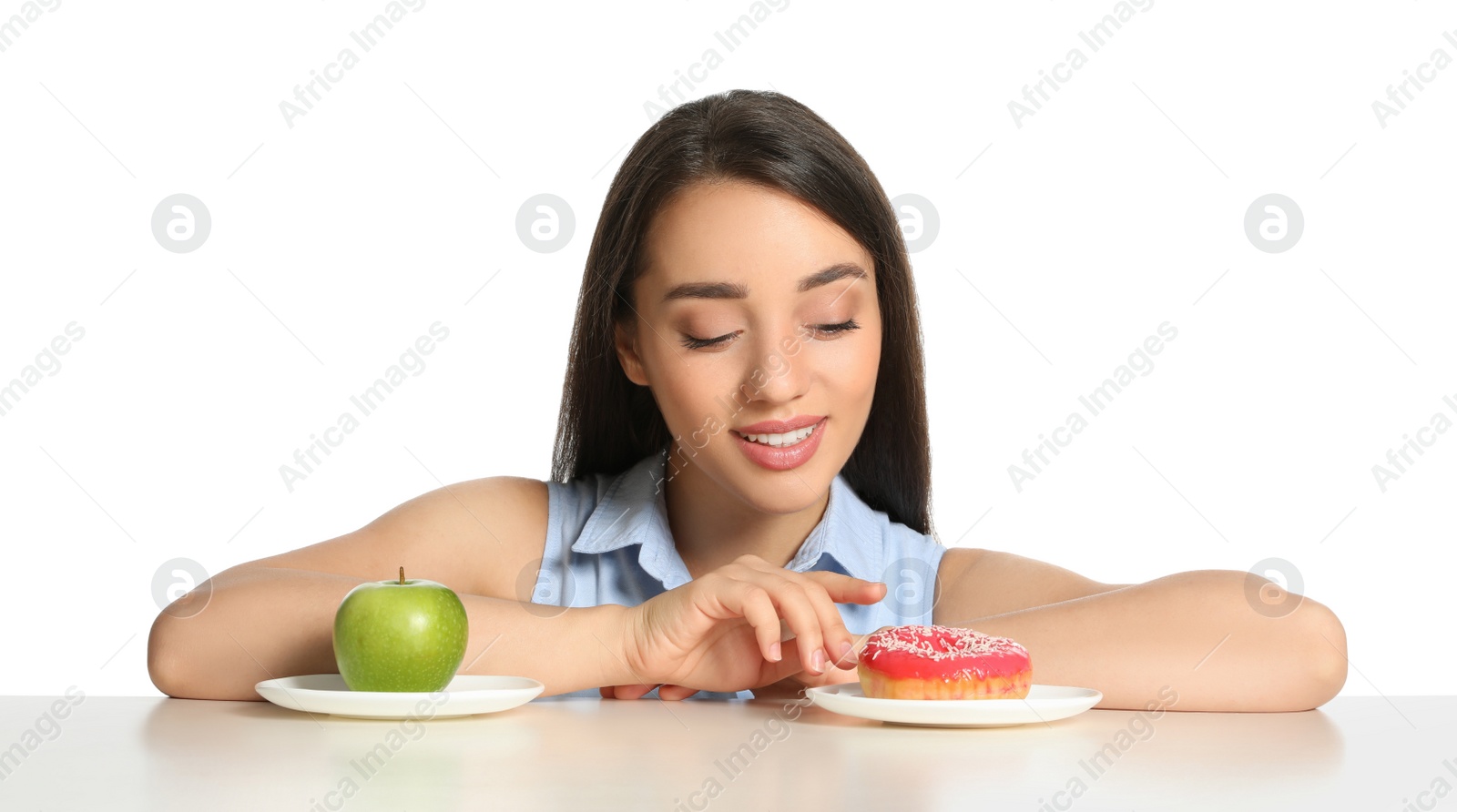 Photo of Woman choosing between apple and doughnut at table on white background