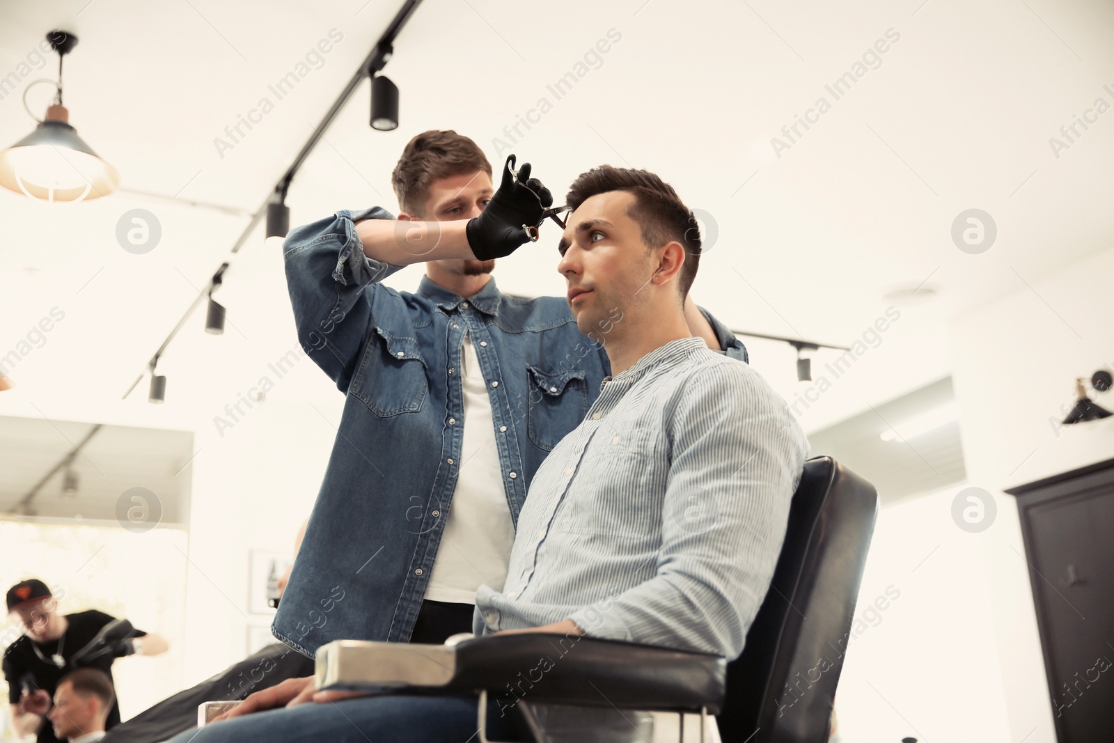 Photo of Professional barber working with client in hairdressing salon. Hipster fashion