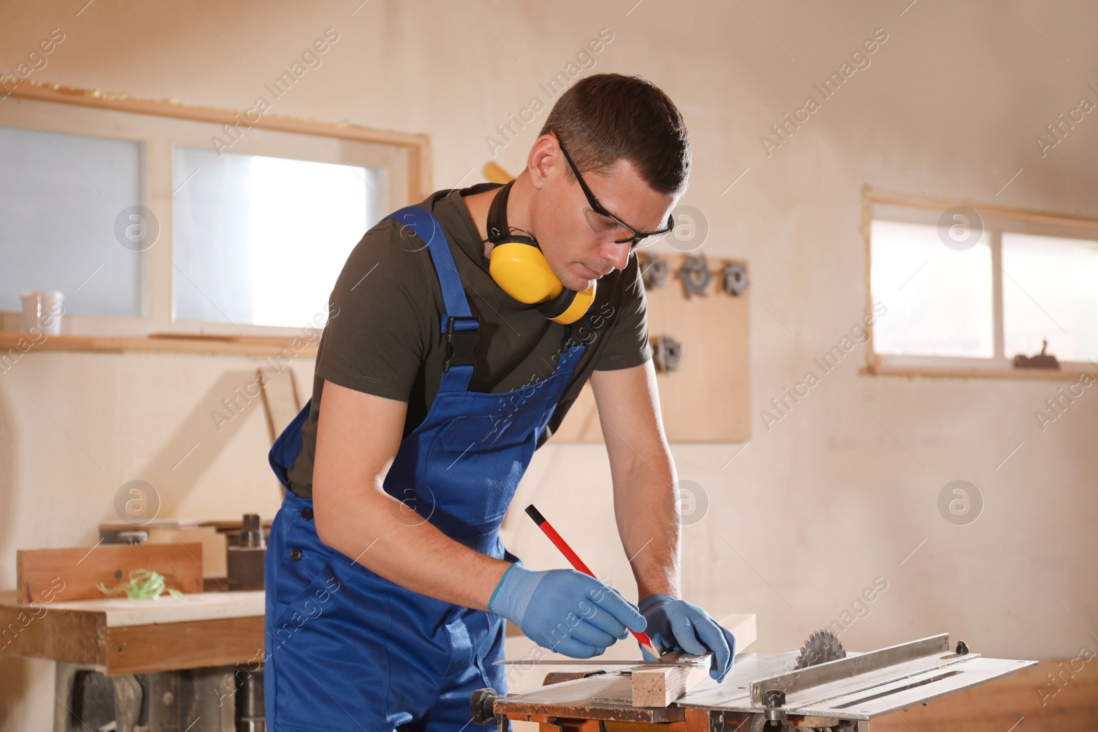 Photo of Professional carpenter making mark on wooden bar in workshop