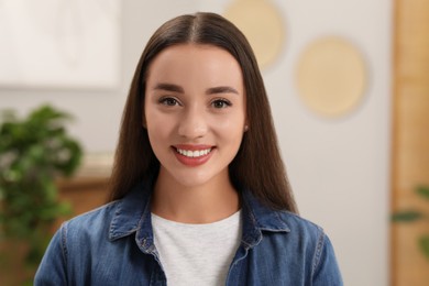 Portrait of beautiful young woman indoors. Attractive lady smiling and looking into camera