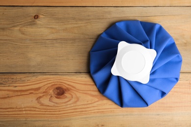 Ice pack on wooden table, top view. Space for text