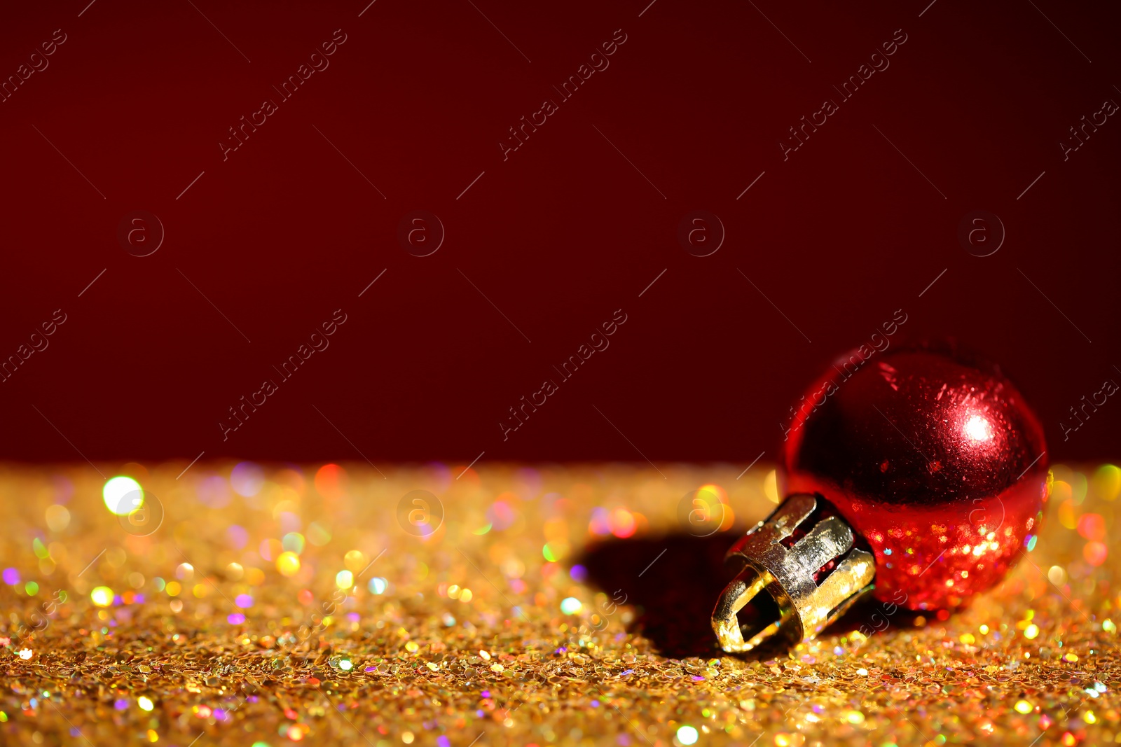 Photo of Golden paillettes and Christmas ball against color background. Space for text