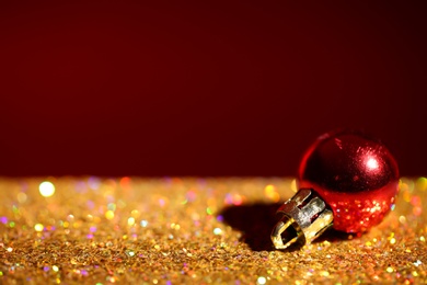 Golden paillettes and Christmas ball against color background. Space for text