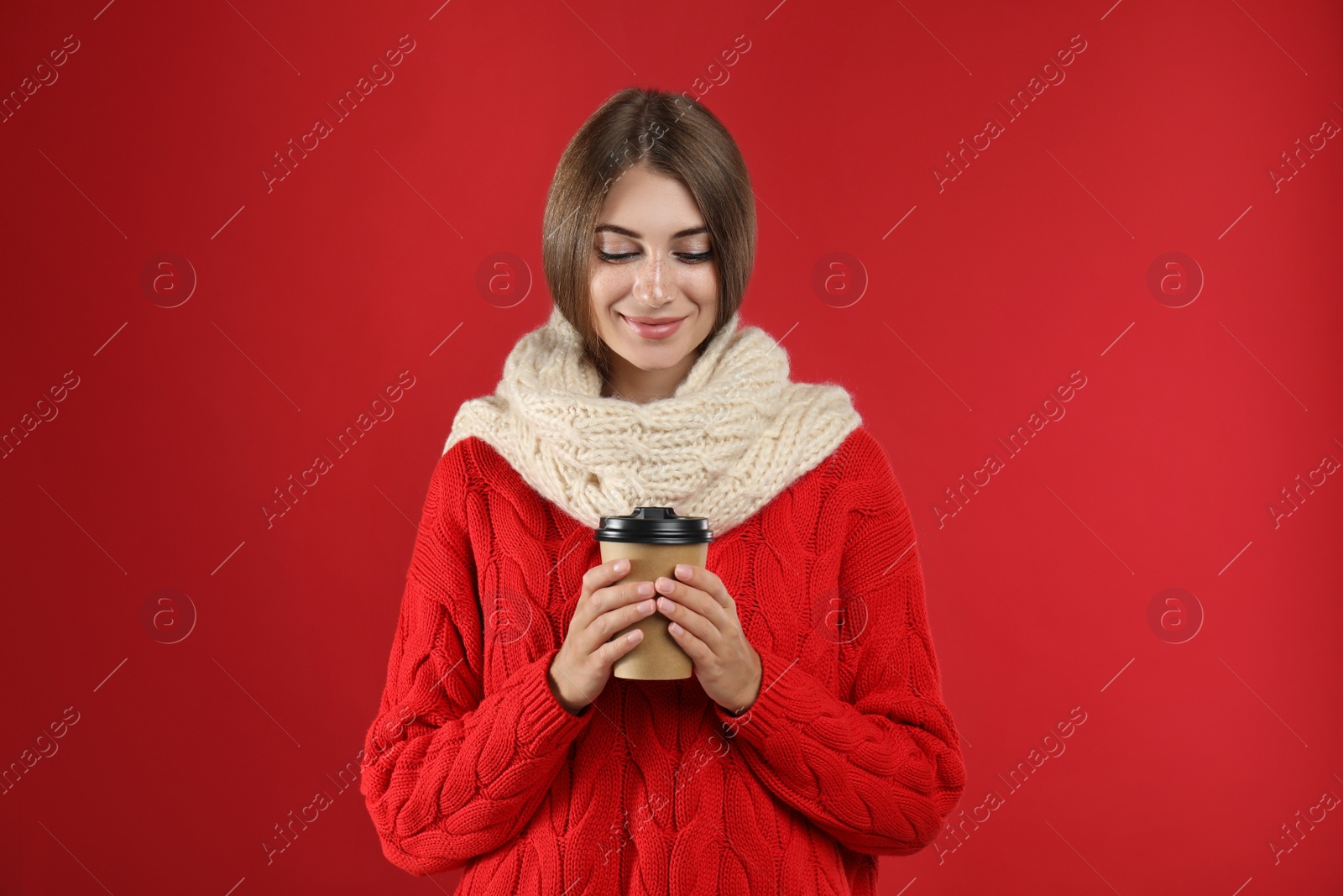 Photo of Happy beautiful woman with paper cup of mulled wine on red background