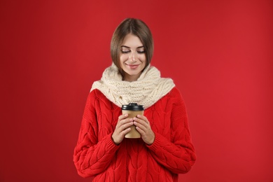 Photo of Happy beautiful woman with paper cup of mulled wine on red background