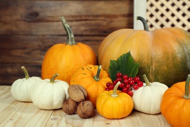 Photo of Happy Thanksgiving day. Composition with pumpkins, walnuts and berries on wooden table, closeup