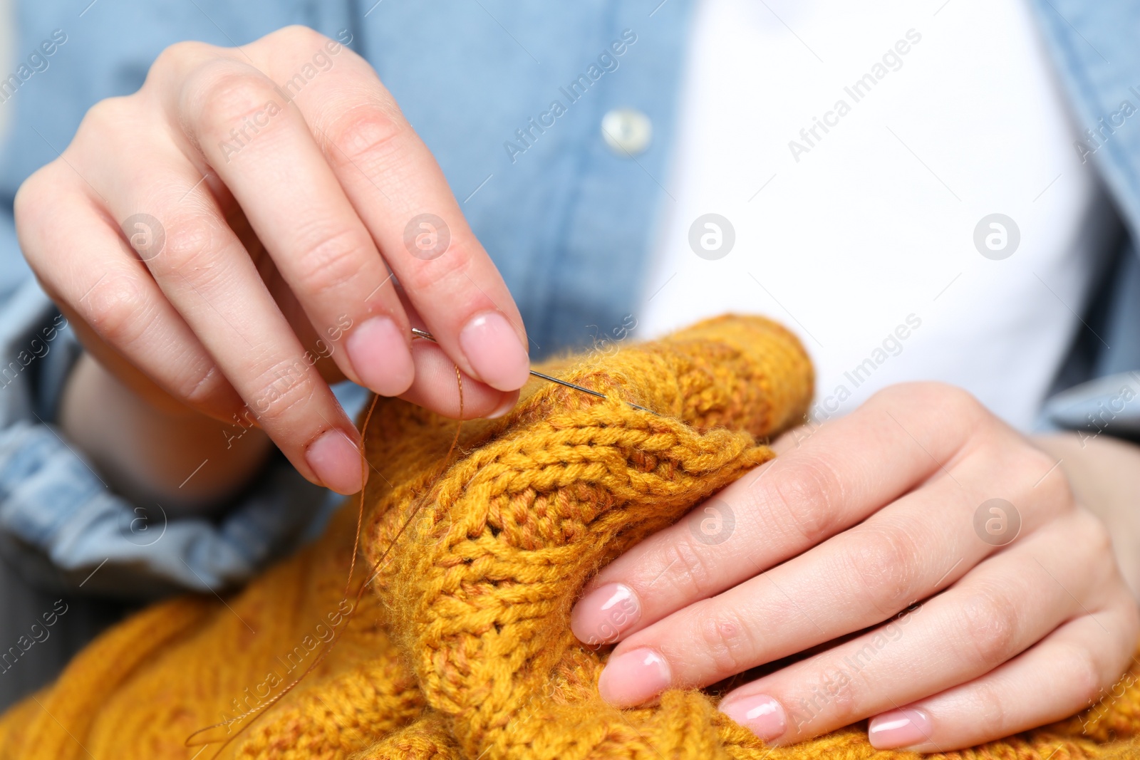 Photo of Woman sewing sweater with needle, closeup view