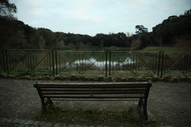 Beautiful view of bench near lake in park on cloudy day