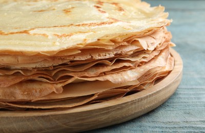 Photo of Stack of delicious crepes on blue wooden table, closeup