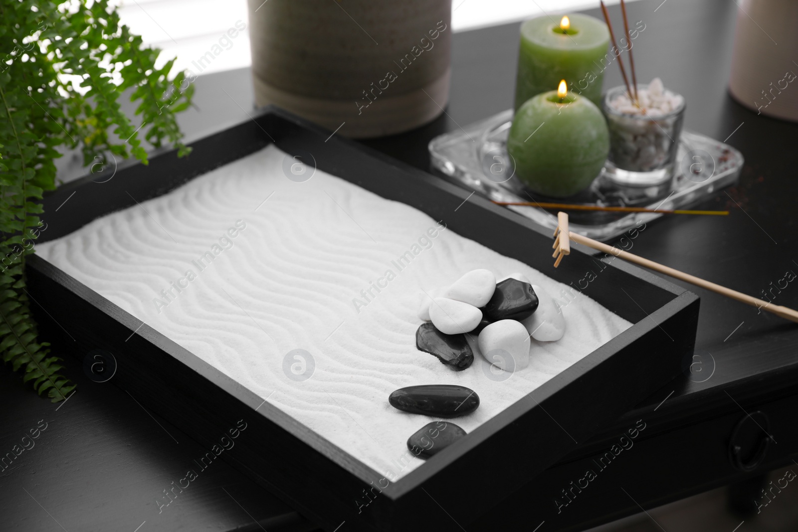 Photo of Beautiful miniature zen garden, candles and incense sticks on black table indoors, closeup