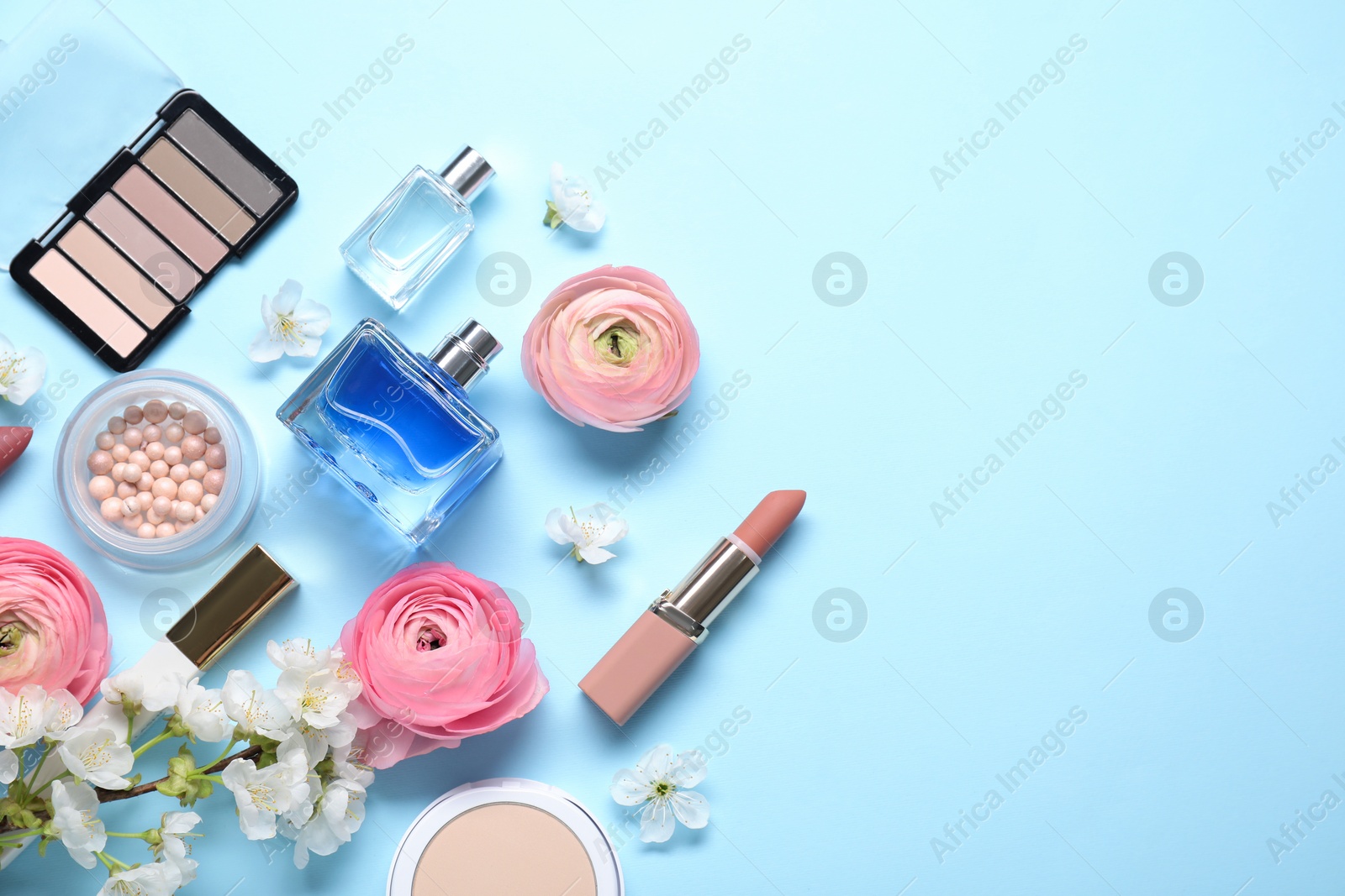 Photo of Flat lay composition with different makeup products and beautiful spring flowers on light blue background, space for text