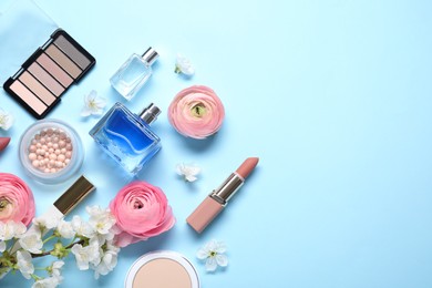 Flat lay composition with different makeup products and beautiful spring flowers on light blue background, space for text